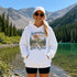 Vintage mountain adventure hoodie featuring a scenic outdoor landscape graphic on a Gildan 18500 Heavy Blend hoodie, shown in a lifestyle mockup. Available in multiple colors with a relaxed unisex fit.