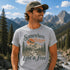 Man wearing a t-shirt with a nature-themed design in a mountainous landscape
