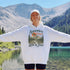 Vintage mountain adventure hoodie featuring a scenic outdoor landscape graphic on a Gildan 18500 Heavy Blend hoodie, shown in a lifestyle mockup. Available in multiple colors with a relaxed unisex fit.