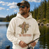 A man wearing a cream-colored hoodie with a graphic of a Bigfoot-style figure fishing and the text 'THE RODFATHER' stands by a lake with trees in the background.