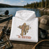 A folded white hoodie with a graphic of a Bigfoot figure holding a fishing rod and a large fish, with the text 'THE ROOFATHER' below, displayed on a wooden dock with a lake and forest in the background. Surrounding props include a fishing rod, tackle box, mug, and a cap reading 'LIFE IS THE LAKE'.