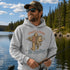 A man wearing a light gray hoodie with a 'Tight Lines No Deadlines' fishing graphic, standing on a lake with a forest background.