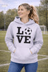 Hoodie with bold LOVE design featuring a soccer ball replacing the O, worn by woman holding coffee cup outdoors
