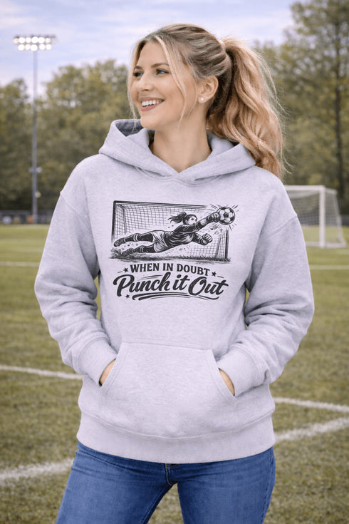 woman wearing hoodie with “When In Doubt Punch It Out” soccer goalie design featuring diving goalkeeper making a save in front of net