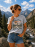 Woman wearing a t-shirt with nature-themed design in a mountainous landscape