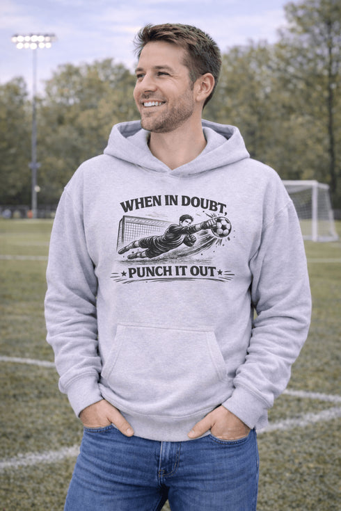 man wearing grey hoodie with “When In Doubt Punch It Out” soccer goalie design featuring diving goalkeeper making a save
