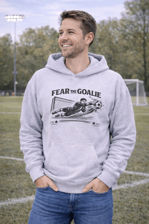 man wearing grey hoodie with “Fear The Goalie” soccer goalkeeper design featuring diving goalie making a save