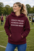 Woman wearing a maroon hoodie with 'Soccer Mom' design on a soccer field.