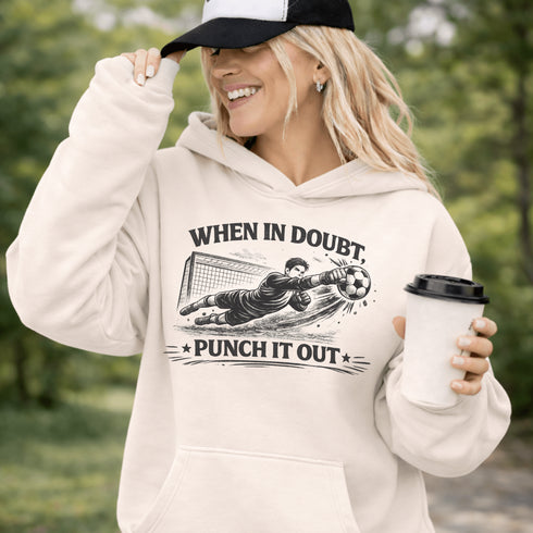 Woman wearing grey hoodie with “When In Doubt Punch It Out” soccer goalie design featuring diving goalkeeper making a save