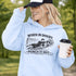Woman wearing grey hoodie with “When In Doubt Punch It Out” soccer goalie design featuring diving goalkeeper making a save