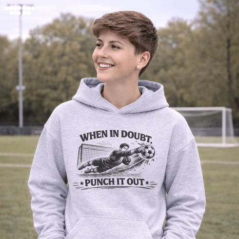 Boy wearing grey hoodie with “When In Doubt Punch It Out” soccer goalie design featuring diving goalkeeper making a save