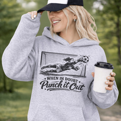 woman wearing hoodie with “When In Doubt Punch It Out” soccer goalie design featuring diving goalkeeper making a save in front of net