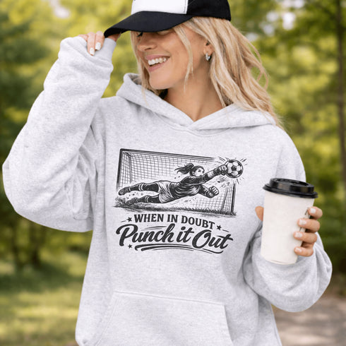 woman wearing hoodie with “When In Doubt Punch It Out” soccer goalie design featuring diving goalkeeper making a save in front of net