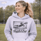 woman wearing hoodie with “When In Doubt Punch It Out” soccer goalie design featuring diving goalkeeper making a save in front of net