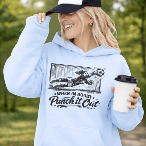 woman wearing hoodie with “When In Doubt Punch It Out” soccer goalie design featuring diving goalkeeper making a save in front of net