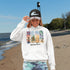 Bring the peaceful charm of Winnipeg Beach with you wherever you go. This soft, comfortable hoodie features a watercolor-style collage celebrating the beauty of Manitoba’s cherished lakeside town.