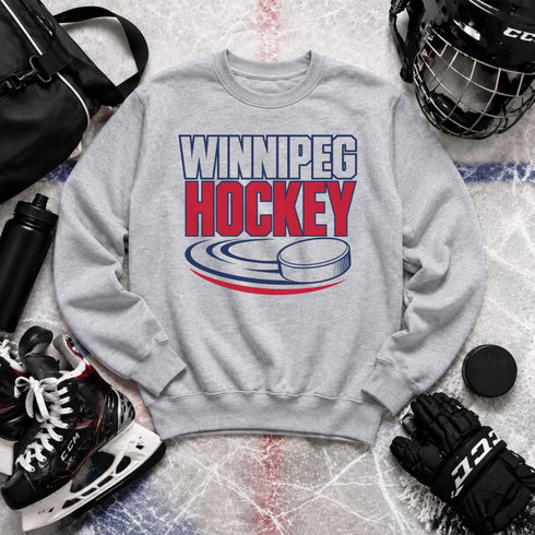 Winnipeg Hockey unisex crewneck sweatshirt featuring vintage navy and red collegiate lettering with a hockey puck graphic, designed by Prairie Life Co.