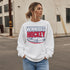 Winnipeg Hockey unisex crewneck sweatshirt featuring vintage navy and red collegiate lettering with a hockey puck graphic, designed by Prairie Life Co.