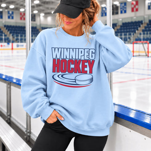 Winnipeg Hockey unisex crewneck sweatshirt featuring vintage navy and red collegiate lettering with a hockey puck graphic, designed by Prairie Life Co.