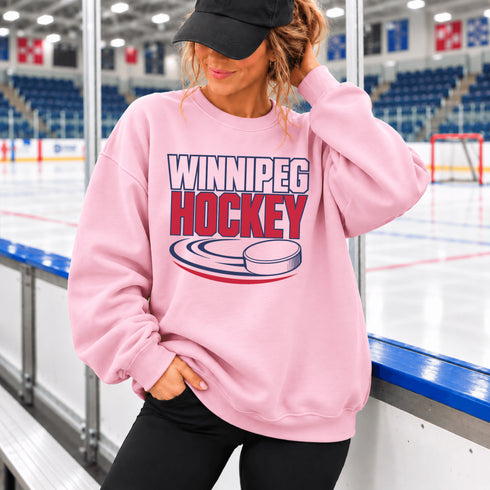 Winnipeg Hockey unisex crewneck sweatshirt featuring vintage navy and red collegiate lettering with a hockey puck graphic, designed by Prairie Life Co.