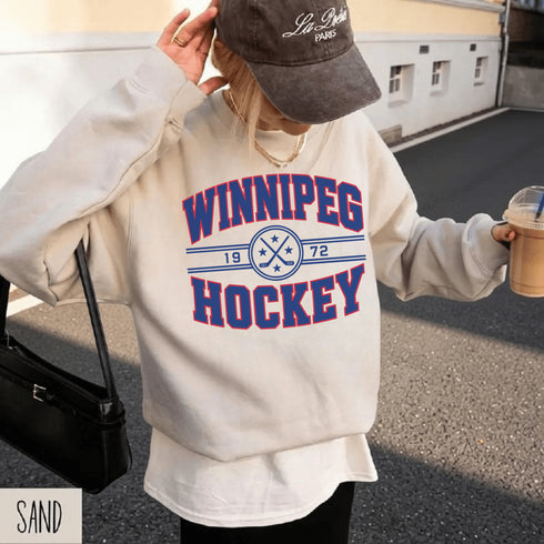 Winnipeg Hockey 1972 vintage-style unisex crewneck sweatshirt with collegiate lettering, crossed hockey sticks and retro hockey graphic by Prairie Life Co.