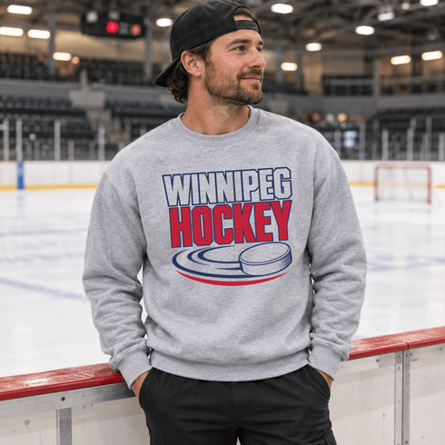 Winnipeg Hockey unisex crewneck sweatshirt featuring vintage navy and red collegiate lettering with a hockey puck graphic, designed by Prairie Life Co.