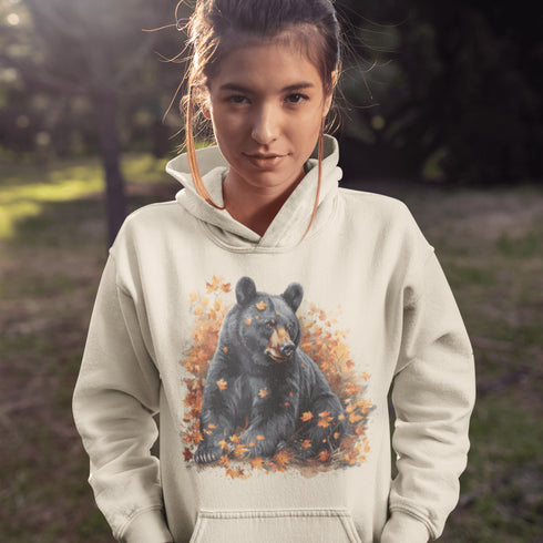 Featuring a detailed graphic of a black bear nestled comfortably among a colorful bed of autumn leaves, this hoodie brings warmth and woodland charm to your wardrobe.