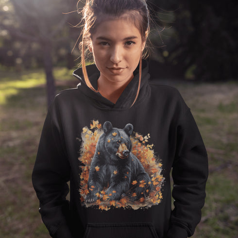Featuring a detailed graphic of a black bear nestled comfortably among a colorful bed of autumn leaves, this hoodie brings warmth and woodland charm to your wardrobe.