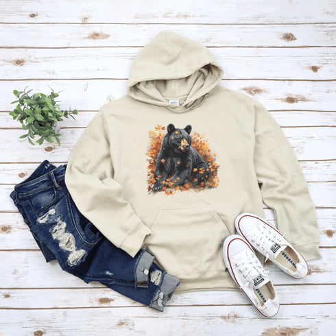 Featuring a detailed graphic of a black bear nestled comfortably among a colorful bed of autumn leaves, this hoodie brings warmth and woodland charm to your wardrobe.