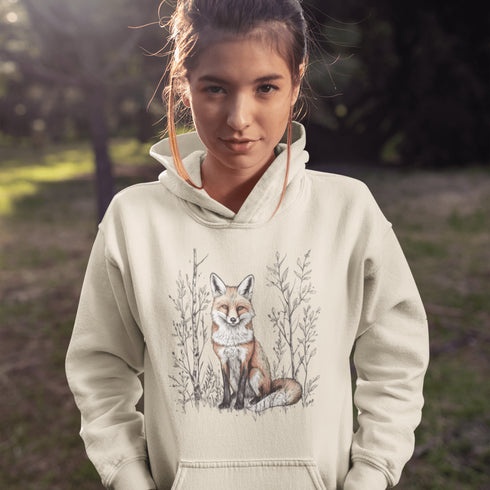 This hoodie features a stunning graphic of a vibrant red fox poised amidst the shadows and light of a lush woodland scene.