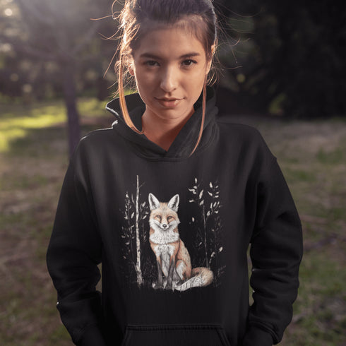 This hoodie features a stunning graphic of a vibrant red fox poised amidst the shadows and light of a lush woodland scene.