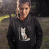 This hoodie features a stunning graphic of a vibrant red fox poised amidst the shadows and light of a lush woodland scene.