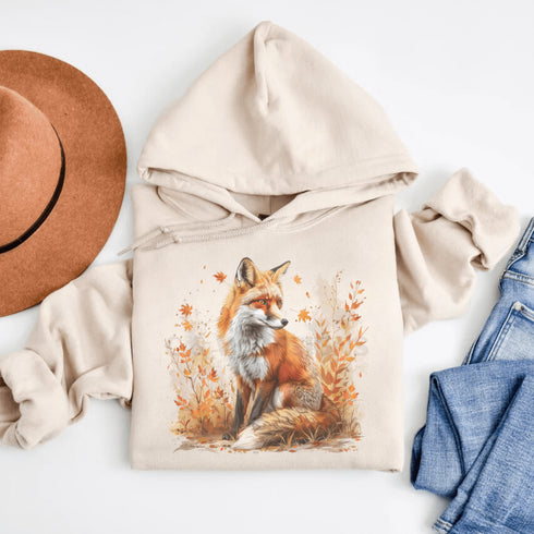 This hoodie features a striking image of a red fox standing alert and proud in its natural habitat, surrounded by lush foliage and the earthy colors of the wilderness.