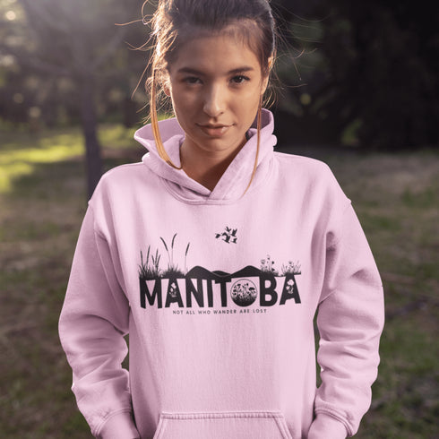 Featuring a prairie landscape, the design showcases wildflowers and prairie grasses blooming from the letters "Manitoba," artfully integrated into the scene.