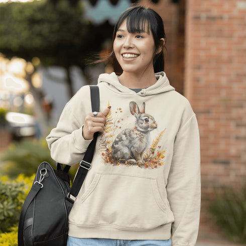 This cozy hoodie features a playful rabbit nestled among vibrant fall foliage, surrounded by the warm oranges, reds, and yellows of the season.