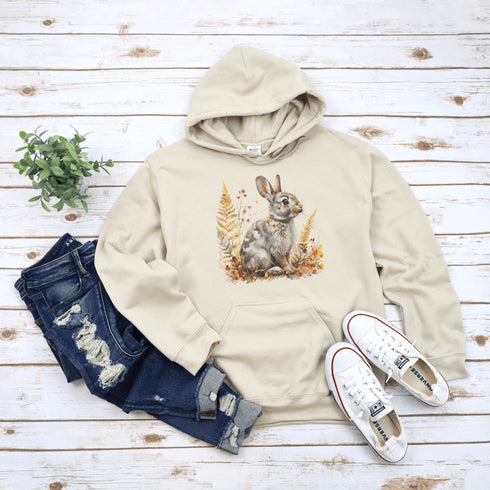 This cozy hoodie features a playful rabbit nestled among vibrant fall foliage, surrounded by the warm oranges, reds, and yellows of the season.