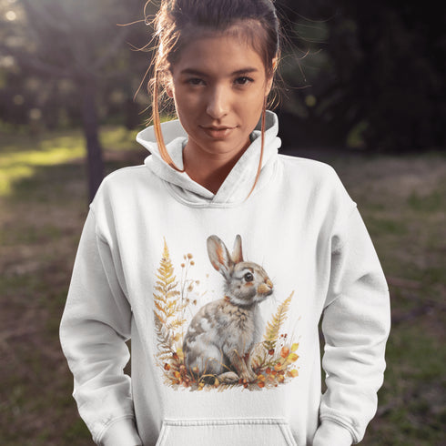 This cozy hoodie features a playful rabbit nestled among vibrant fall foliage, surrounded by the warm oranges, reds, and yellows of the season.