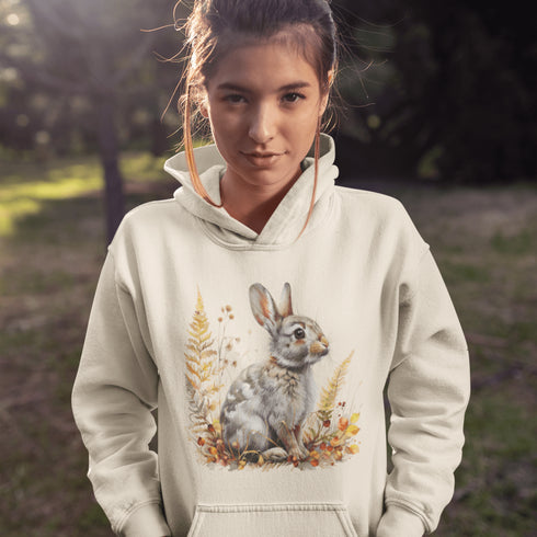 This cozy hoodie features a playful rabbit nestled among vibrant fall foliage, surrounded by the warm oranges, reds, and yellows of the season.
