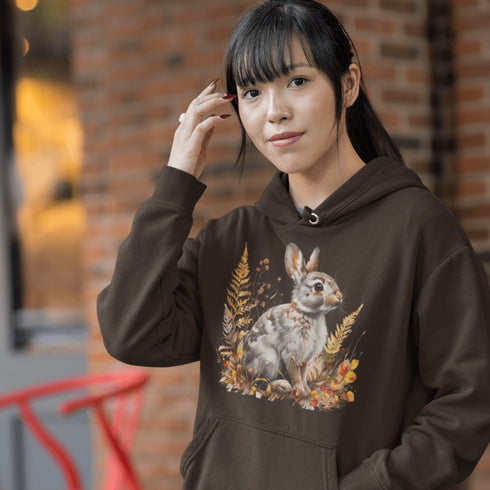 This cozy hoodie features a playful rabbit nestled among vibrant fall foliage, surrounded by the warm oranges, reds, and yellows of the season.