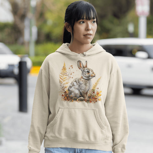 This cozy hoodie features a playful rabbit nestled among vibrant fall foliage, surrounded by the warm oranges, reds, and yellows of the season.