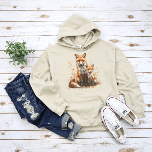 This beautifully crafted hoodie showcases a loving mother fox and her playful kit sitting in a cozy bed of fall foliage, surrounded by vibrant autumn leaves.