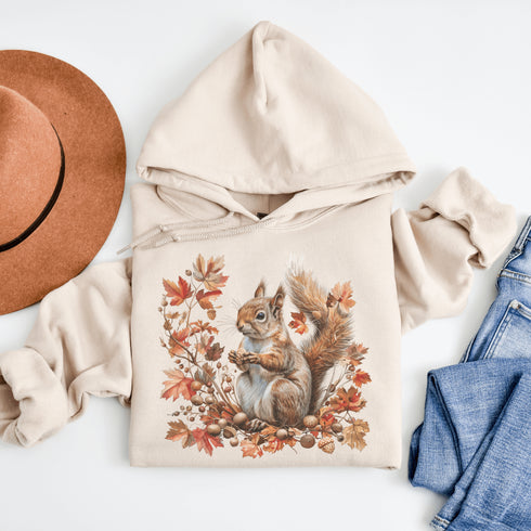 Get ready for fall with the Acorn Gatherer Hoodie, featuring an adorable squirrel surrounded by autumn foliage and a stash of acorns.