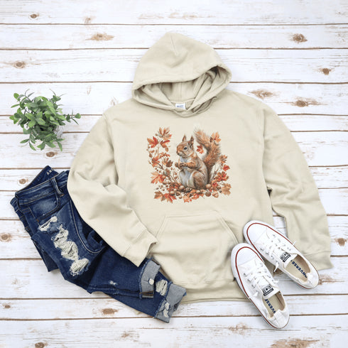 Get ready for fall with the Acorn Gatherer Hoodie, featuring an adorable squirrel surrounded by autumn foliage and a stash of acorns.