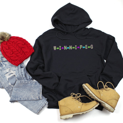 This picture showcases the Winnipeg Retro Gaming Hoodie that has a bold green gaming font with space creatures separating the Winnipeg Letters