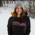 This gender neutral hoodie features A Winnipeg City Skyline and colored retro Stripes across the front.