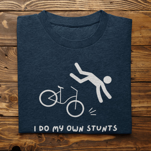 Introducing our latest masterpiece in the world of fashion disasters - the "I Do My Own Stunts" t-shirt! Picture this: a daring stick figure attempting to defy gravity on a bike, only to end up in a spectacular crash landing.