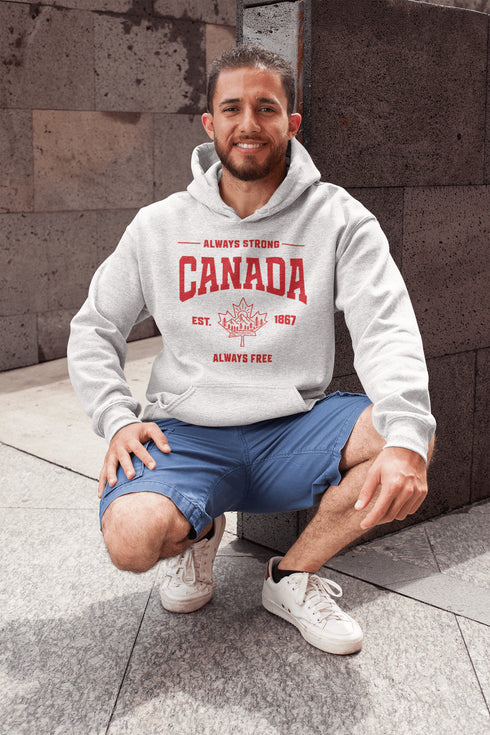 Woman wearing grey Canada Always Strong hoodie with red maple leaf graphic and “Est. 1867” design, styled outdoors in a natural setting