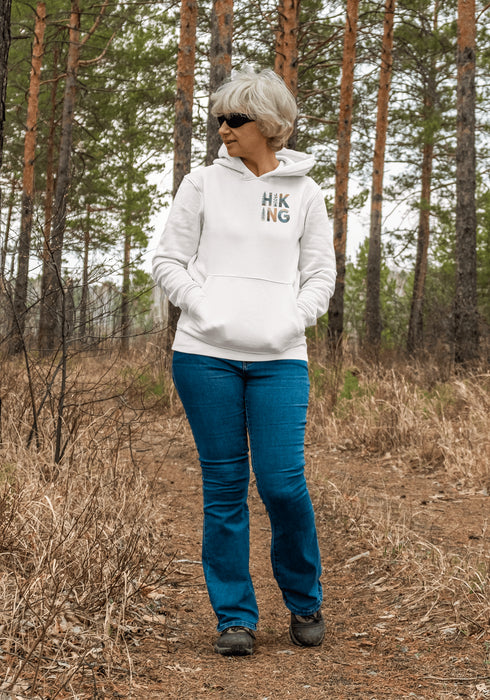 woman wearing hiking hoodie with large nature graphic on back walking in the forest