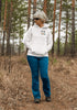 woman wearing hiking hoodie with large nature graphic on back walking in the forest