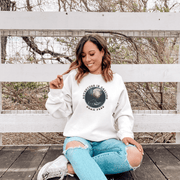 This gender neutral crewneck sweatshirt features a stunning design of a grizzly bear roaming on a campsite with the moon shining behind it. The saying "Adventure Is Calling Roam Free" is printed boldly, capturing the essence of the great outdoors and the spirit of camping. Perfect for any outdoor adventure